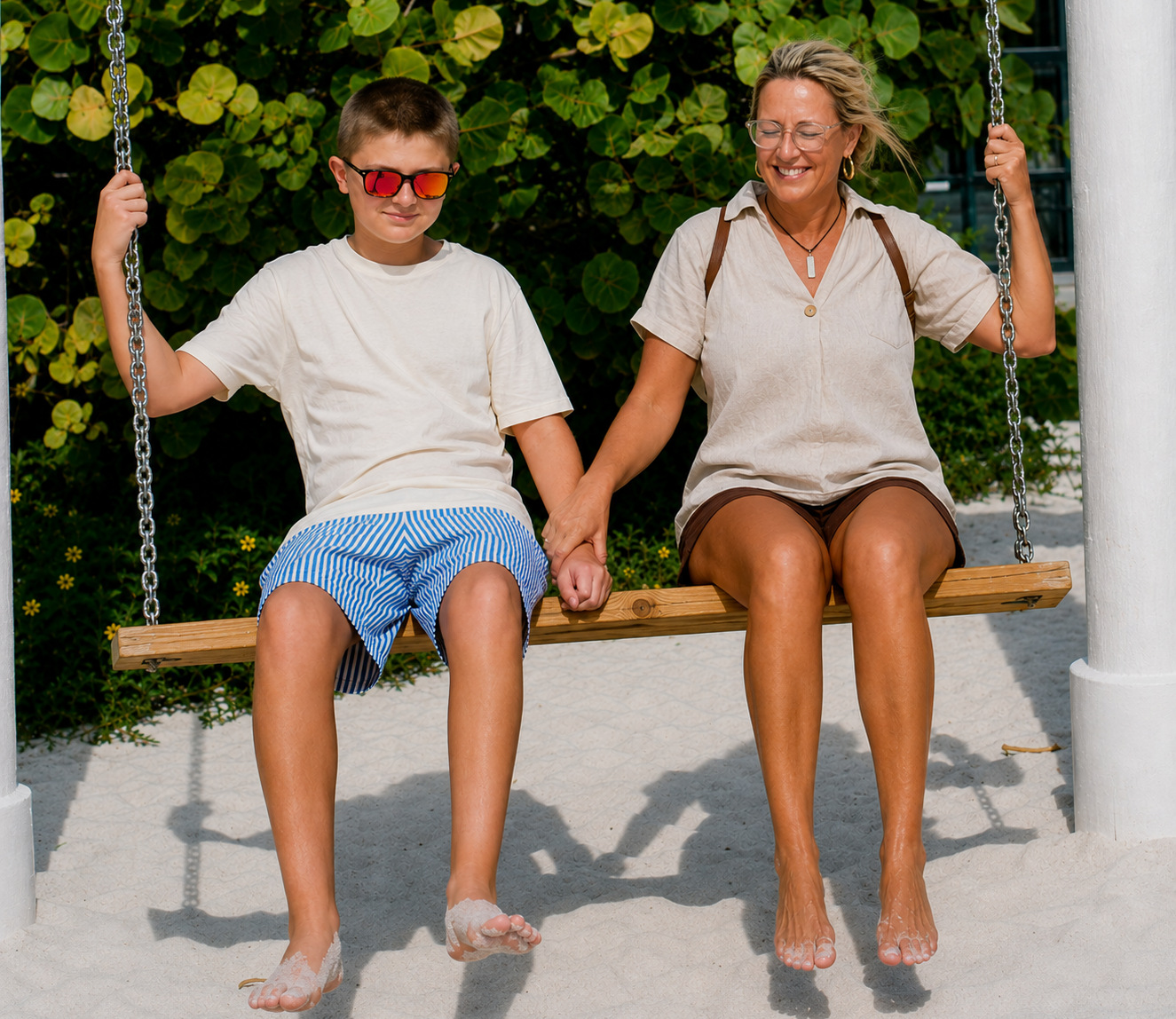 Angie and her son smiling together on a beach swing